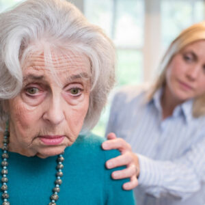 Elderly woman looking concerned, younger woman providing support.