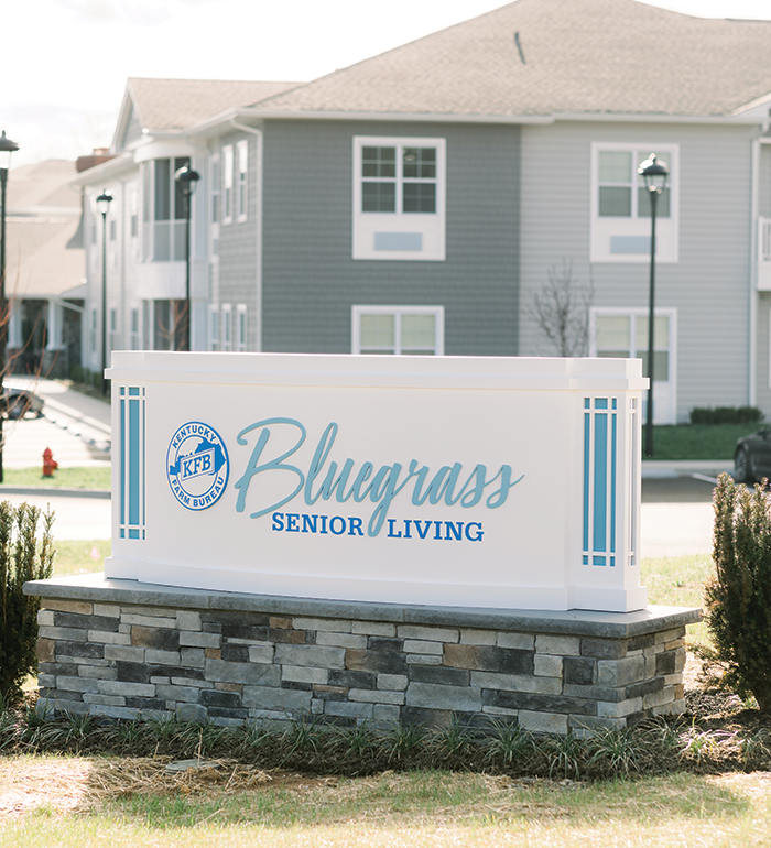 Sign for Bluegrass Senior Living facility with gray buildings.
