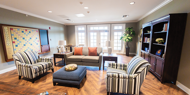 Cozy living room with seating, bookshelves, and natural light.