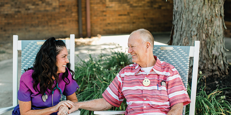 Smiling nurse and patient enjoying a pleasant conversation outside.