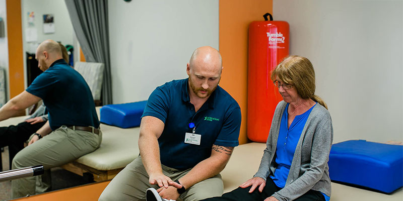 Physical therapist assisting a patient with leg exercise.