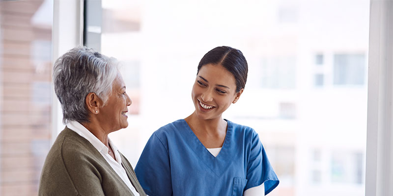 Nurse and elderly woman sharing a warm conversation.